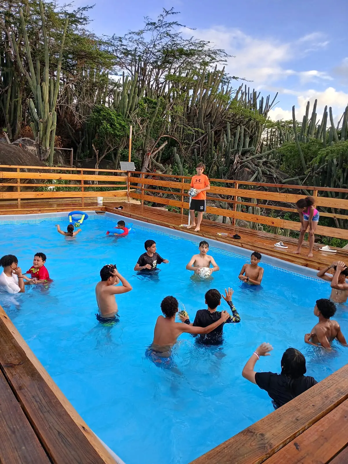 Children playing in the pool at Mi Dushi Casibari, with a wooden deck and cacti behind